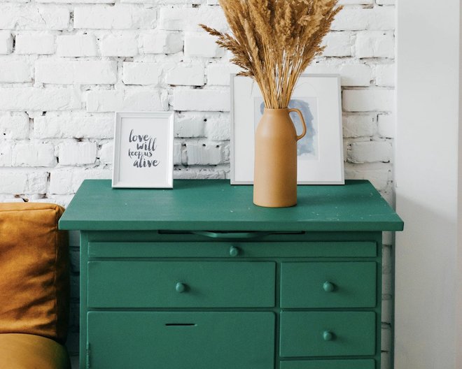 vase and frame with text standing on a dark green drawer